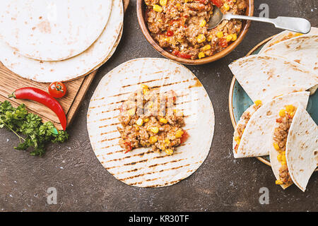 Hausgemachtes Rindfleisch mexikanische Fajitas mit Paprika, Mais und Tortillas auf dunklem Hintergrund, Ansicht von oben Stockfoto