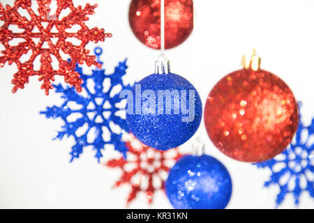 Schöne Weihnachten und Neujahr bunten Hintergrund. In der Nähe von rot und blau leuchtenden Ornamenten hängend auf glänzendem Silber Seile isoliert auf Weiss. Hor Stockfoto