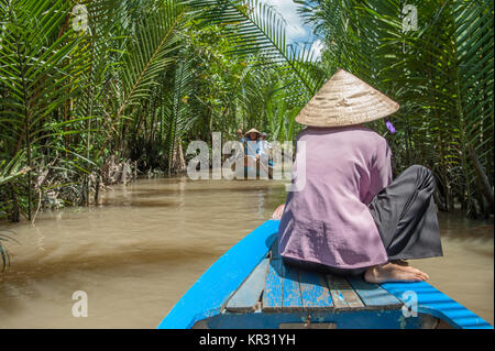 Vietnamesin Paddeln ein traditionelles Boot im Mekong Delta in Ben Tre Insel. Der Fluss Mekong ist eine wichtige Route für den Transport im Südosten Stockfoto