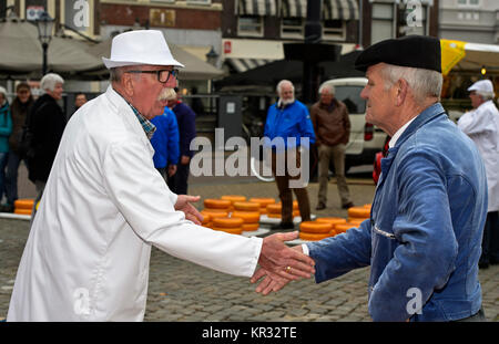 Ein Käse, der Kaufmann, Links, und ein Bauer, rechts, Feilschen um den Preis von Gouda Käse auf dem Käsemarkt, Gouda, Niederlande Stockfoto