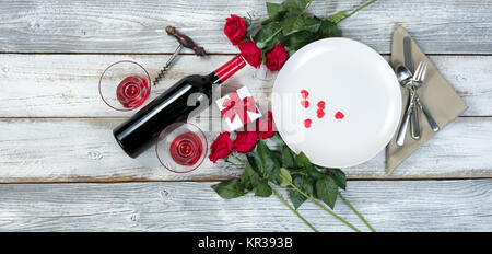 Valentine Abendessen mit Geschenk, rote Rosen, Wein und Herzen Formen auf rustikalen Tisch Stockfoto