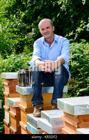 Imker mit Smoker sitzen auf seine Bienenstöcke Stockfoto