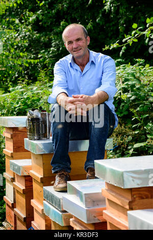 Imker mit Smoker sitzen auf seine Bienenstöcke Stockfoto