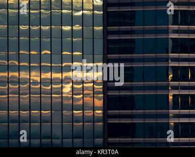 Sonnenaufgang oder Sonnenuntergang reflektiert das Glas Fenster Fassade auf ein hohes Gebäude. Stockfoto