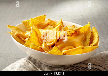 Einzelne Ovale weiße Schüssel gelb Tortilla Chips mit geschmolzenem Käse auf gefalteten Stoff Serviette über Tischdecke mit Kopie Raum platziert Stockfoto