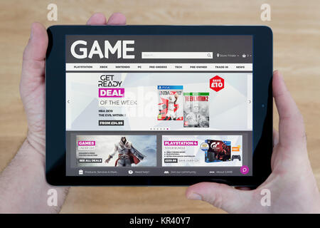 Ein Mann schaut auf der Website des Spiels auf seinem iPad tablet device, Schuß gegen einen hölzernen Tisch top Hintergrund (nur redaktionelle Nutzung) Stockfoto