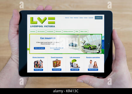 Ein Mann schaut auf die Liverpool Victoria Website auf seinem iPad tablet device, Schuß gegen einen hölzernen Tisch top Hintergrund (nur redaktionelle Nutzung) Stockfoto
