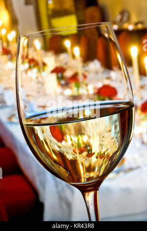 Wein TISCH KERZEN FORMALE VERKOSTUNG Feiner weißer Wein Glas in den Vordergrund einer förmlichen Sitzen bei Kerzenschein Dinner Party Tisch hinter Stockfoto