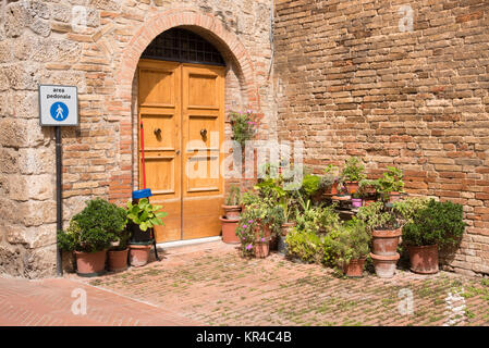 Holztür mit den Blumentöpfen in der mittelalterlichen toskanischen Stadt San Gimignano Stockfoto