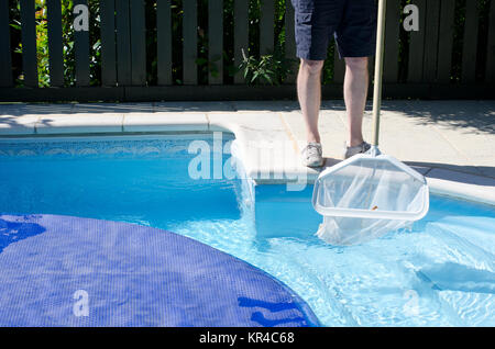 Ein Mann mit einem Netz den letzten Teil des Pools reinigen, bevor der Deckel geht auf Stockfoto