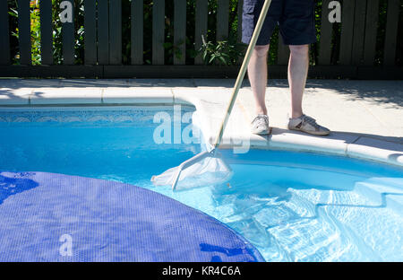 Ein Mann mit einem Netz den letzten Teil des Pools reinigen, bevor der Deckel geht auf Stockfoto