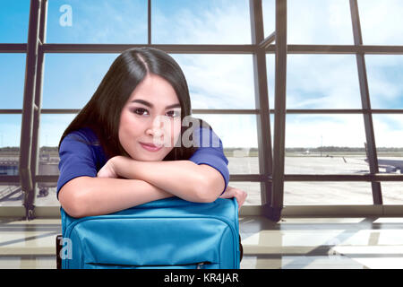 Lächelnd asiatische Frau mit Koffer warten Abflug im Flughafen Stockfoto