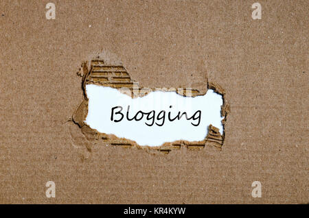 Das Wort Blogging erscheint hinter zerrissenes Papier Stockfoto