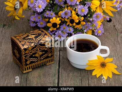 Kaffee, Sarg und Bouquet von wilden Blumen auf einem Holztisch Stockfoto