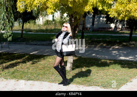 die schöne Frau mit einer Tasche geht im Herbst auf die Städte Stockfoto