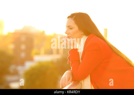 Seitenansicht Portrait von eine ernste nachdenkliche Frau in einem Haus Balkon im Winter bei Sonnenuntergang Stockfoto