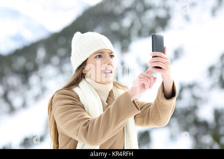 Verzweifelte frau Suche Handy Abdeckung im Winter Urlaub in die schneebedeckten Berge Stockfoto