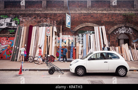 Fußgänger vorbei Teppiche für Verkauf an Sclater Straße Fleat Markt im East End von London. Stockfoto