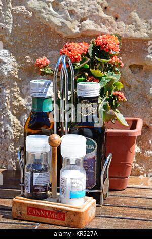 Salz, Pfeffer, Olivenöl und Essig mit Blumen auf der Rückseite der auf einem Holztisch innerhalb der Zitadelle, Victoria (Rabat), Gozo, Malta, Europa. Stockfoto