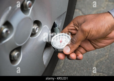 Person mit Manometer für die Messung des Reifendrucks Stockfoto