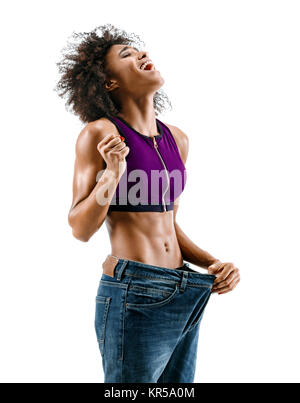 Sportliche Mädchen ihre großen Jeans ziehen und Gewichtsverlust. Foto der afrikanischen Mädchen auf weißem Hintergrund. Kraft und Motivation Stockfoto