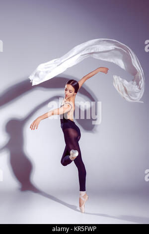 Ballerina aus schwarzem Outfit posiert auf Zehen, Studio-Hintergrund. Stockfoto