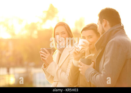 Drei lustige Freunde sprechen und im freien Kaffee trinken bei Sonnenuntergang Stockfoto