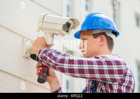 Techniker installieren die Kamera an der Wand Stockfoto