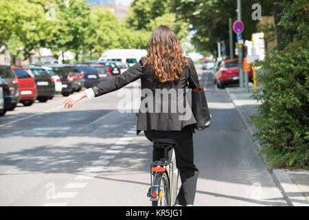 Junge Geschäftsfrau und zeigt damit auf dem Fahrrad Stockfoto