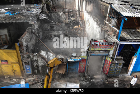 Mumbai. 18 Dez, 2017. Eine Baumaschine löscht Rückstände von einem Feuer Unfall in Mumbai am Dez. 18, 2017. Mindestens 12 Menschen wurden getötet und vier andere in ein Großbrand in einem Geschäft in der indischen Hauptstadt verletzt Montag, sagte die Polizei. Quelle: Xinhua/Alamy leben Nachrichten Stockfoto