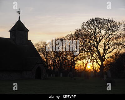 Harty, Kent, Großbritannien. 18 Dez, 2017. UK Wetter: Ein schöner Winter Sonnenuntergang hinter der Kirche 'St. Der Apostel Thomas' (Grad II) nach der 11. oder frühen 12. Jahrhundert, an Harty auf der Insel Sheppey in Kent. Oft als Kent's entlegensten Ort der Anbetung beschrieben. Credit: James Bell/Alamy leben Nachrichten Stockfoto