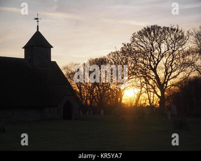 Harty, Kent, Großbritannien. 18 Dez, 2017. UK Wetter: Ein schöner Winter Sonnenuntergang hinter der Kirche 'St. Der Apostel Thomas' (Grad II) nach der 11. oder frühen 12. Jahrhundert, an Harty auf der Insel Sheppey in Kent. Oft als Kent's entlegensten Ort der Anbetung beschrieben. Credit: James Bell/Alamy leben Nachrichten Stockfoto