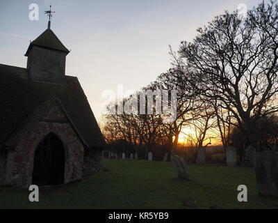 Harty, Kent, Großbritannien. 18 Dez, 2017. UK Wetter: Ein schöner Winter Sonnenuntergang hinter der Kirche 'St. Der Apostel Thomas' (Grad II) nach der 11. oder frühen 12. Jahrhundert, an Harty auf der Insel Sheppey in Kent. Oft als Kent's entlegensten Ort der Anbetung beschrieben. Credit: James Bell/Alamy leben Nachrichten Stockfoto