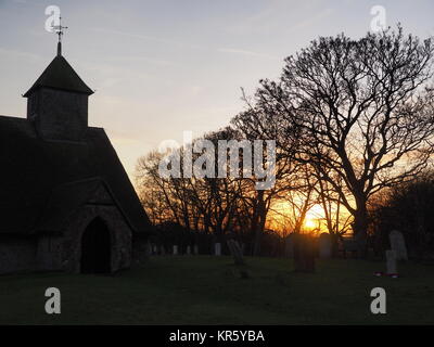 Harty, Kent, Großbritannien. 18 Dez, 2017. UK Wetter: Ein schöner Winter Sonnenuntergang hinter der Kirche 'St. Der Apostel Thomas' (Grad II) nach der 11. oder frühen 12. Jahrhundert, an Harty auf der Insel Sheppey in Kent. Oft als Kent's entlegensten Ort der Anbetung beschrieben. Credit: James Bell/Alamy leben Nachrichten Stockfoto