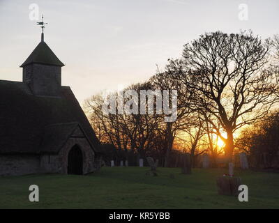 Harty, Kent, Großbritannien. 18 Dez, 2017. UK Wetter: Ein schöner Winter Sonnenuntergang hinter der Kirche 'St. Der Apostel Thomas' (Grad II) nach der 11. oder frühen 12. Jahrhundert, an Harty auf der Insel Sheppey in Kent. Oft als Kent's entlegensten Ort der Anbetung beschrieben. Credit: James Bell/Alamy leben Nachrichten Stockfoto