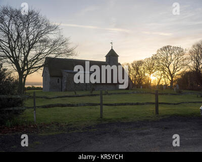 Harty, Kent, Großbritannien. 18 Dez, 2017. UK Wetter: Ein schöner Winter Sonnenuntergang hinter der Kirche 'St. Der Apostel Thomas' (Grad II) nach der 11. oder frühen 12. Jahrhundert, an Harty auf der Insel Sheppey in Kent. Oft als Kent's entlegensten Ort der Anbetung beschrieben. Credit: James Bell/Alamy leben Nachrichten Stockfoto