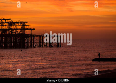 Brighton, East Sussex. Dezember 2017 19. UK Wetter. Bright Red Skies bei Sonnenuntergang am Ende des Tages, wo eine Herde von Tausende von Staren, die auf eine murmuration Anzeige oberhalb von Brighton West Pier. Credit: Francesca Moore/Alamy leben Nachrichten Stockfoto