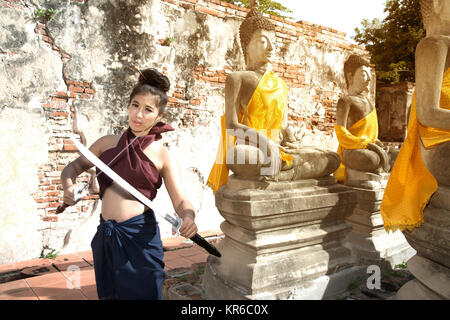 Hübsche Asiatin in der Thailändischen alten Krieger am Wat Phutthaisawan Tempel in Ayutthaya Historical Park, Thailand posieren. Stockfoto