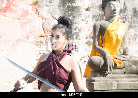 Hübsche Asiatin in der Thailändischen alten Krieger am Wat Phutthaisawan Tempel in Ayutthaya Historical Park, Thailand posieren. Stockfoto