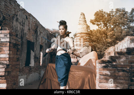Hübsche Asiatin in der Thailändischen alten Krieger am Wat Phutthaisawan Tempel in Ayutthaya Historical Park, Thailand posieren. Stockfoto