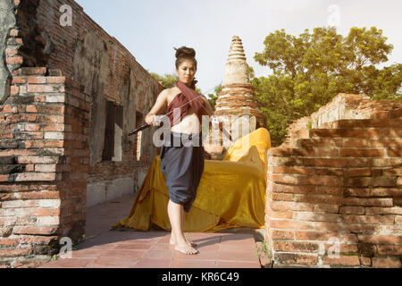 Hübsche Asiatin in der Thailändischen alten Krieger am Wat Phutthaisawan Tempel in Ayutthaya Historical Park, Thailand posieren. Stockfoto