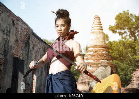Hübsche Asiatin in der Thailändischen alten Krieger am Wat Phutthaisawan Tempel in Ayutthaya Historical Park, Thailand posieren. Stockfoto