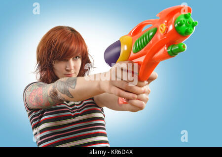 Foto eines wunderschönen redhead über zu einem Wasser Gewehr schießen. Stockfoto