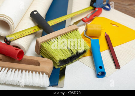 Rollen von Tapeten und verschiedene Werkzeuge zum Tapezieren. Stockfoto