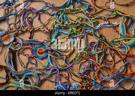 Andere Gewirke bunte Armbänder und Ohrringe sind chaotisch auf dem Tisch liegen. Stockfoto