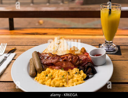 Geniessen ein grosses Frühstück mit Eiern, Speck, tomats, Würste, Brot, Ketchup, musrooms und eine Frucht Getränk in Ao Nang in Thailand Stockfoto