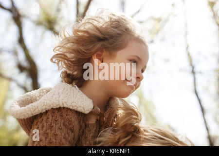 Kleine niedliche Mädchen sitzen auf den Schultern der Mutter. Herbst im Freien. Stockfoto