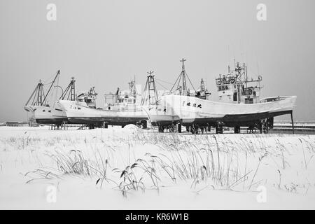 Reihe von Fischerbooten auf trockenen Plattformen im Winter. Stockfoto