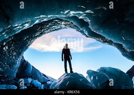 Rückansicht Silhouette der Person, die auf Eis rock am Eingang zu einem gletschereis Höhle. Stockfoto