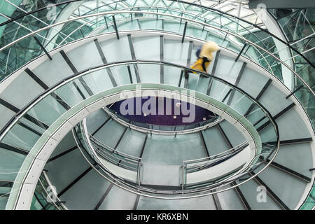 Innenansicht des Gebäudes mit person Wandern auf Glas und Metall Wendeltreppe. Stockfoto